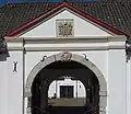 Tor eines Vierkanthofs mit Giebel und Wappen