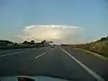Cumulonimbuswolke über dem in etwa 25&nbsp;km Entfernung liegenden Stadtgebiet von Apolda, fotografiert um Sonnenuntergang von etwas östlich von Erfurt aus