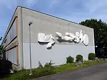 Kalligraphie. Entwurf zum Relief aus Marmor 1975 von Helene Balmer. Ausführung von Lorenz Balmer, 1982. (Breite 12,5 Meter). Sekundarschule II Fröschmatt, Pratteln