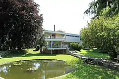 Teich, Garten und hinter dem Haus Schminke der Schornstein der Anker-Fabrik