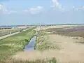 Aufgegebenes Streckenstück zwischen Cecilienkoog und Lüttmoorsiel (der ehemalige Bahndamm ist rechts des Kanals zu erkennen)