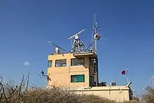Zweistöckiger Betonbau mit Antennen und anderen technischen Geräten auf dem Flachdach