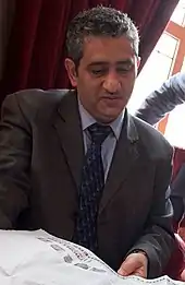 Mansoor Al-Jamri, ein Mann im Anzug und grauem Haar, liest eine Zeitung