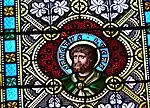 Detail eines Glasfensters im Kirchenschiff mit dem Apostel Lukas