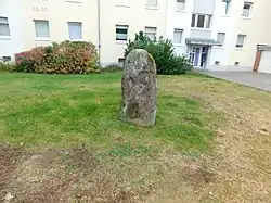 Blick auf den Menhir vor einer Hausfassade