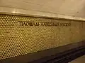 Wand über einem der Gleise mit dem Stationsnamenschriftzug