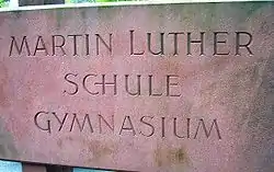Name der Schule als Sandsteinrelief