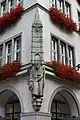 Skulptur, die das Kaufingertor auf den Schultern eines Goldschmieds darstellt