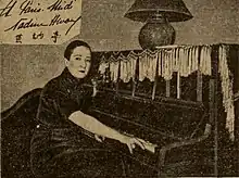 Nadine Hwang ist sitzend an einem Klavier zu sehen. Sie schaut in die Kamera und trägt kurzes Haar. Die Fotografie ist in Sepia.