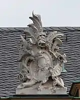 8. Trophäe – Baumstamm, Lanzenfahne, Trompete, Kartusche, Schild, Handspiegel, Rosen. Kopie von Dachfigur 6.