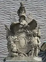 22. Trophäe – Liktorenbündel, Helm, Schwerter, Kugel, Adler, Löwe, Putto, Rosengirlande, Lanzenfahnen, Kartusche mit den Initialen CC von Herzog Carl Eugen.