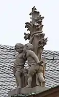 46. Trophäe: Ludus (Spiel) − 2 Putten, Baumstamm, Löwe, Widder.