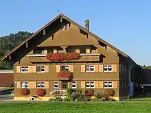 zweigeschossiger, verschindelter Bau mit aufgesteiltem Satteldach