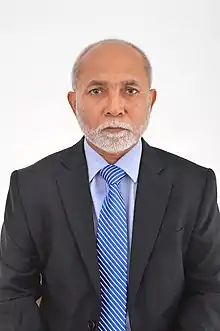 Hussain Rasheed Ahmed, ein dunkelhäutiger älterer Mann mit kurzgeschorenen Haaren im Anzug mit einer blauen Krawatte