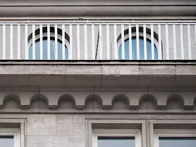 Detailfoto mit Reling, Rundbogenfries und den Faschen der Fenster.