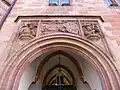 Eh. Durchfahrt zum Innenhof, Portal mit Landsknechten und wappentragendem Engel, Bildhauer der Landsknechte: Wilhelm Schneider (1907), Bildhauer des wappentragenden Engels: Heinrich Wagner (1907); Die Durchfahrt war ursprünglich mit einem reich profilierten, zweiflügeligen hölzernen Tor aus dem Jahr 1899 geschlossen.