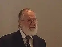 Porträtfoto von Reinhard Bölling von 2016, nach rechts blickend mit Brille, zurückgekämmten Haaren und weißen Vollbart