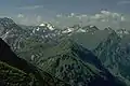 Giebel (der Berg mit dreieckiger, teilweise bewaldeter Flanke am rechten Bildrand) vom Nordwestgrat des Älpelekopf. Der grasige Berg in Bildmitte im Vordergrund ist der Roßkopf. Etwas rechts oberhalb im Hintergrund der Schneck. Am linken Bildrand der Glasfelderkopf. Gegenüber dem Schneck der Große Wilde mit der schneegefüllten Gamswanne. Zwischen Schneck der Großen Wilden der Himmelecksattel.