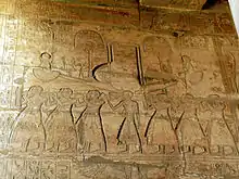 Relief mit Reihen von Männern, die Stangen tragen, die ein Modellboot stützen