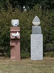 Lorenz Balmer-Gerber (1916–2004), Helen Balmer-Gerber (1924), Gemeinschaftswerk. Skulptur, Frau mit Weihgabe und Wächter, 1993. Granit, Marmor, Kalk- und Sandstein für das anonyme Gemeinschaftsgrab, Friedhof am Hörnli, Basel.