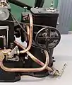 Spritzbürstenvergaser des Stationärmotors von 1887. Der Antrieb im Vordergrund lässt die Bürste rotieren.