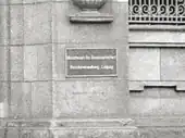 Schwarze geriffelte Metalltafel mit weißen Buchstaben, die in zwei Zeilen zeigen „Ministerium für Staatssicherheit“ und „Bezirksverwaltung Leipzig“