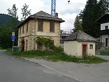 Bahnhof Tai di Cadore (Kilometer 5,738) mit separatem Toilettengebäude im Vordergrund, die Bahnlinie verlief links vom Stationsgebäude