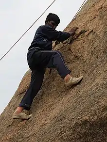 Ein Mann mit Klettergurt an einer Felswand