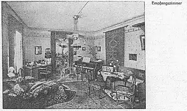 Repräsentativ gestaltetes Empfangszimmer des Töchterpensionats Wieler mit Schreibtisch der Vorsteherin, Frauenbüste, Flügel, Sofa und Chaiselongue mit Überwurf