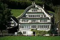 Fabrikanten- und Handelshaus mit Schweifgiebeldach aus dem Jahr 1813, Eingang mit Rundbogenportal und über Ost- und Westseite durch­laufendem Klebdach in Spreitenbach, Brunnadern