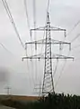 Donaumast mit drei Ebenen und vier Systemen (220/110&nbsp;kV), dahinter Betonmast einer Mittelspannungsleitung