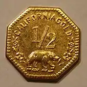 Eine achteckige Goldmünze, unter der Zahl 1/2 ist ein Bär abgebildet, darüber steht CALIFORNIA GOLD