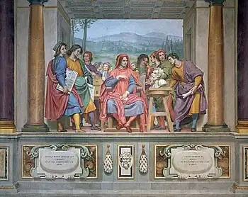 Ölgemälde einer Männergruppe in Togen, die in einem Raum mit Säulen und einer Landschaft im Hintergrund stehen. Der mittlere Mann sitzt und blickt mit den anderen auf eine Büste, die rechts auf einem Hocker steht. Der Raum endet vorne mit einer Kante, die wie eine Wandvertäfelung gemalt ist. Daran sind verzierte Tafeln sowie ein Reliefkopf angebracht.