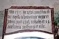 Die lateinische Inschrift über dem Fenster der rechten Apsiswand besagt, dass die Kapelle 1515 wiedergeweiht wurde zur Ehre der Jungfrau Maria, der Apostel Petrus und Paulus, der Heiligen Michael, Wolfgang und Ottilie und der 14 Nothelfer. Die Laibung des Fensters ist mit Ranken verziert.