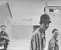 Befreite jüdische Gefangene - einer trägt einen deutschen Stahlhelm - lächeln in die Kamera