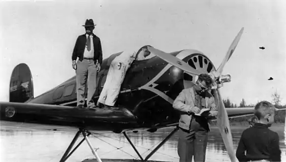 Will Rogers auf der Tragfläche und Wiley Post im Vordergrund mit Augenklappe, Fairbanks (Aug. 1935)