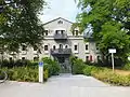 1906/07 durch Friedrich von Thiersch erbaute Walmdachvilla in Jugendstilformen in der Mandlstraße 1, davor befindet sich ein 1907 von Mathias Gasteiger gestalteter Brunnen mit zwei Jugendstil-Hermen