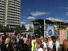 Eine Demonstration durch eine größere Straße, ein „Party“-Anhänger mit Lautsprechern und Bannern fährt mit, auf dem Anhänger sind unter anderem die Buchstaben L O V E