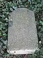 Privater Grabstein auf dem Massengrab, umgestürzt