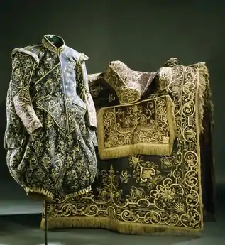 Galagewand von Gustav II. Adolf von Schweden (es fehlen Kragen, Manschetten und Bänder oder Schleifen), dahinter Prunk-Satteldecke (Livrustkammaren, Schweden)